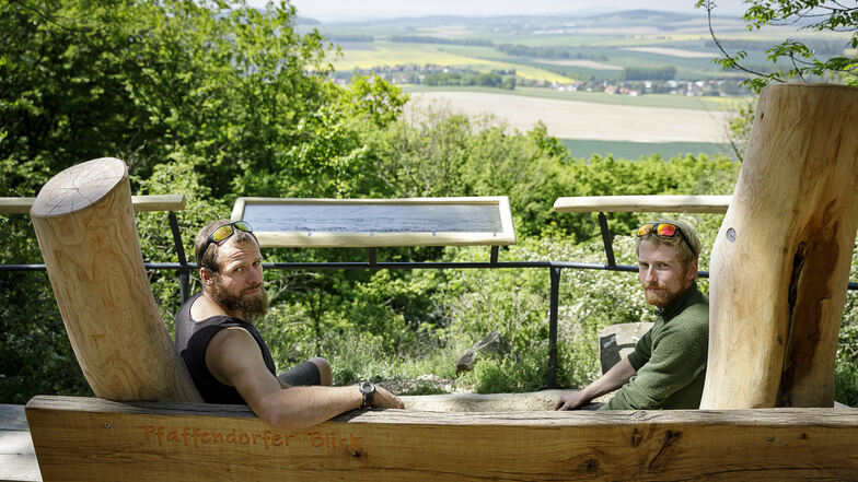 Christoph Kretzschmar (links) und Philipp Weise von der Firma Holzgestalten aus Ostritz sitzen vor der neuen Panorama-Tafel am Aussichtspunkt Pfaffendorfer Blick auf der Landeskrone.