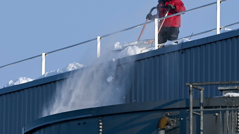 Ein Arbeiter schippt Schnee vom Dach des Amazon Logistiklagers in Leipzig.