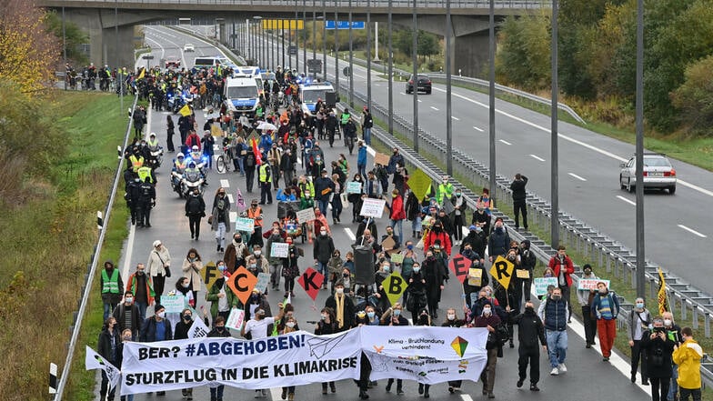 Demonstranten laufen auf einer Straße in Richtung des Hauptstadtflughafens Berlin Brandenburg.