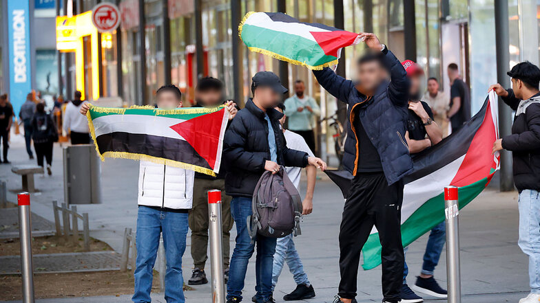 Gegendemonstranten einer Israel-Solidaritätskundgebung in Chemnitz schwenken mehrere Fahnen.