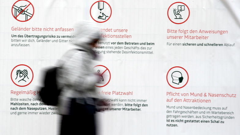 Eine Frau geht in Düsseldorf an einem Plakat mit Hinweisen zum Schutz vor dem Coronavirus vorbei. Die Impfungen nehmen zu und es werden Lockerungen der Corona-Beschränkungen für Geimpfte und Genesene geprüft.