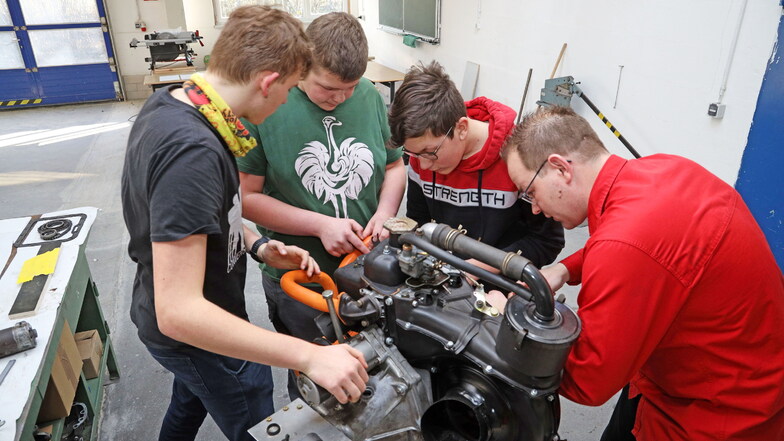 Von links nach rechts: Jonas (16), Finn (13) und Linus (14) arbeiten gemeinsam mit Samuel Wagner am Wiederaufbau eines Fiat-500-Motors. Es ist nur eins der Angebote in der Offenen Werkstatt in Riesa.