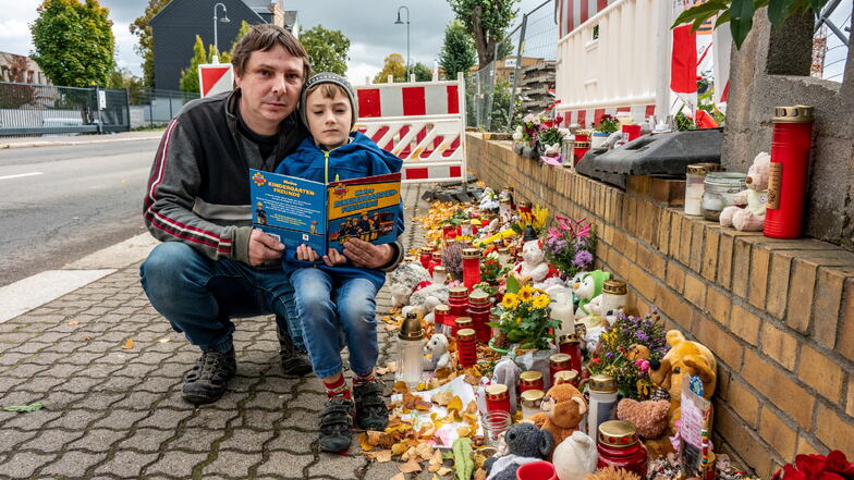 Thomas Schneider mit seinem Sohn Enzo (7) an der Unfallstelle in Hartha, an der viele Menschen Kerzen aufgestellt und Blumen niedergelegt haben.