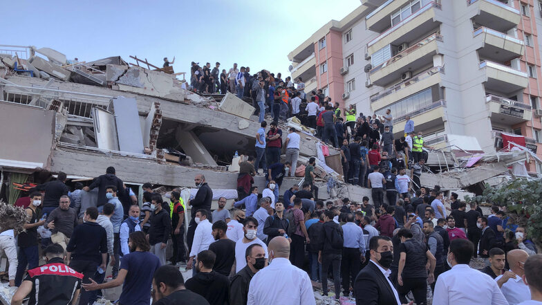 Rettungskräfte und Anwohner in Izmir versuchen Menschen, die in den Trümmern eines eingestürzten Gebäudes eingesperrt sind, zu erreichen.