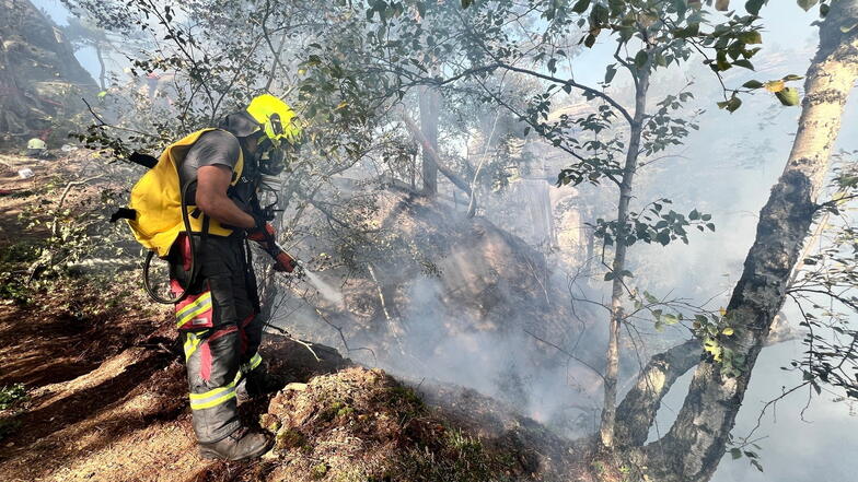 Schwerstarbeit für die Feuerwehrleute: Im schwierigen Gelände des Pfaffensteins müssen sie Glutnester unschädlich machen.