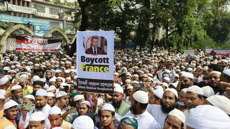 Aktivisten der islamistischen Partei Islami Andolan Bangladesh halten bei einem Protest gegen Frankreich ein Schild mit einer durchgestrichenen Abbildung des französischen Präsidenten Macron hoch.