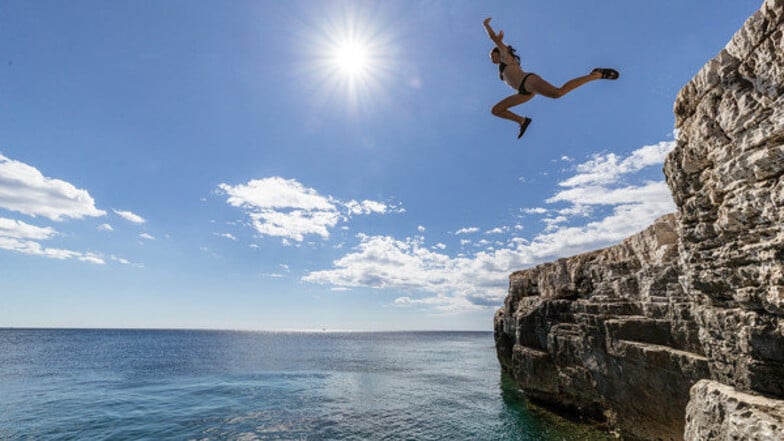 Nahe dem kroatischen Städtchen Pula springt ein Mädchen von der Klippe ins Wasser. Wie bevölkert werden die Buchten diesen Sommer?