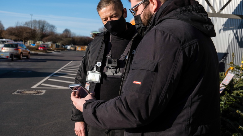 Stephan Stolle (links) von der Sicherheitsfirma GRS Görlitzer Service GmbH überprüft vor einem Baumarkt den Corona-Impfstatus bei Kunden. Für das Bild bei seinem Kollegen Lucas Schmidt.