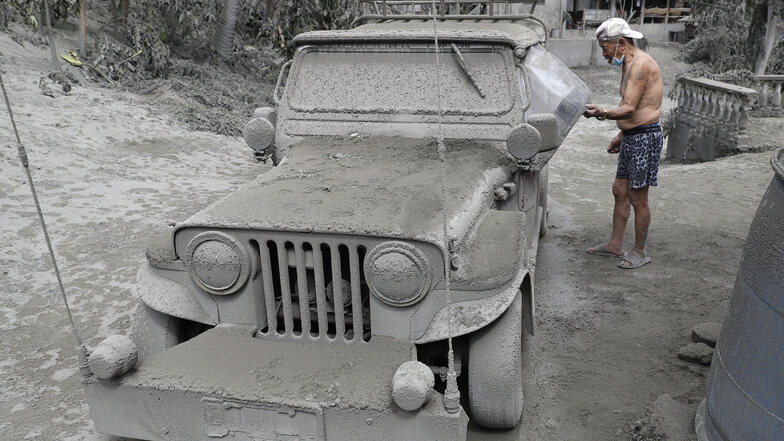 Ein Bewohner kontrolliert seinen mit Vulkanasche bedeckten Jeep vor seinem Haus in Laurel in der Provinz Batangas. 