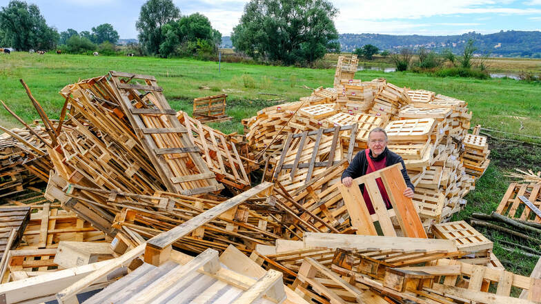 Künstler Reinhard Zabka steht mitten in einem Berg von Holzpaletten und -kisten. Es ist das Baumaterial für sein Labyrinth auf der Elbwiese. Eigentlich sollte der Haufen komplett verschwunden und zu neuen fantastischen Gebilden verbaut sein.