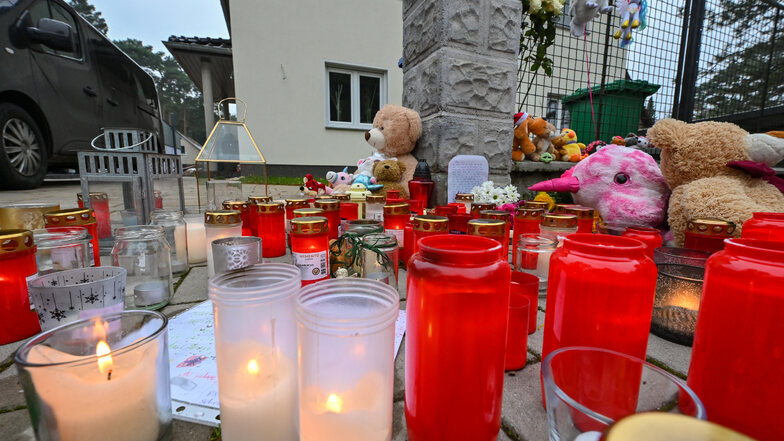 Viele Kerzen brennen vor einem Einfamilienhaus in einem Ortsteil der Stadt Königs Wusterhausen. Am Samstag hatten Zeugen in diesem Einfamilienhaus leblose Personen gesehen und die Polizei alarmiert.