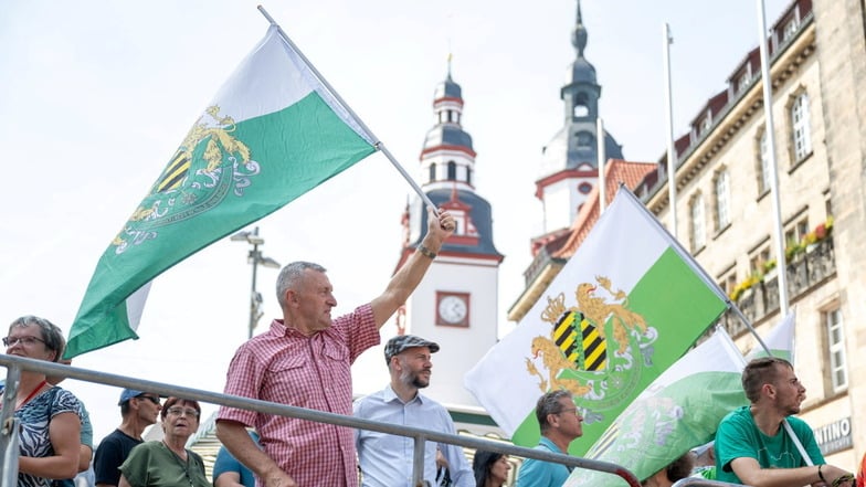 Teilnehmer einer Protestkundgebung der Partei "Freie Sachsen" stehen am Rande des Wahlkampfabschlusses der SPD in Chemnitz.