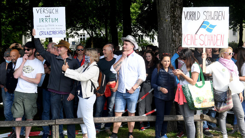 München: Teilnehmer einer Demonstration gegen die Anti-Corona-Maßnahmen der Politik stehen mit Transparenten am Rand der Theresienwiesen.