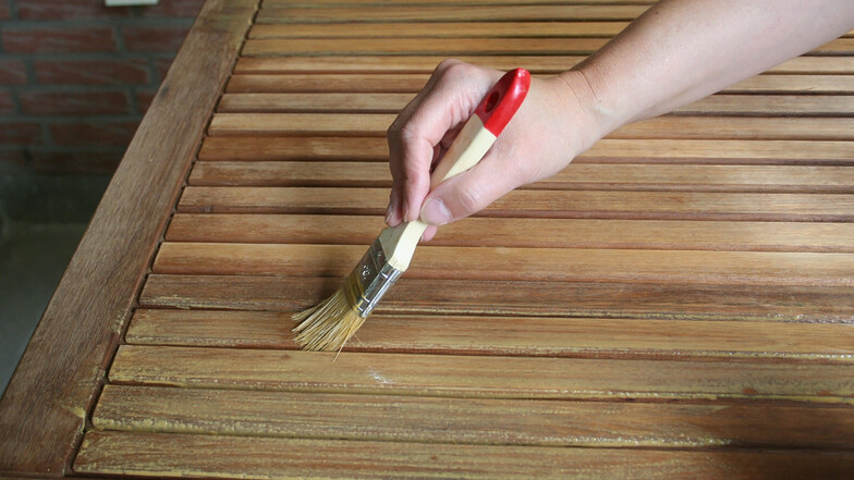 Holz-Öl wird mit einem Pinsel dünn und gleichmäßig aufgetragen.