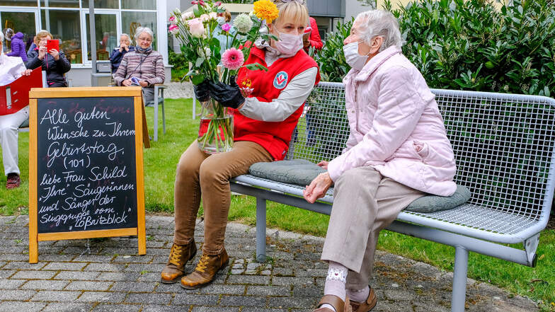 Mehr Nähe: Nach dem dritten Lied nimmt die Jubilarin Margareta Schild bei ihren Sangesfreunden im Innenhof Platz. Wohnparkleiterin Katrin Hanitsch überreicht der 101-Jährigen einen großen Blumenstrauß. „So ein Jubiläum haben wir noch nie gehabt“, sagt sie
