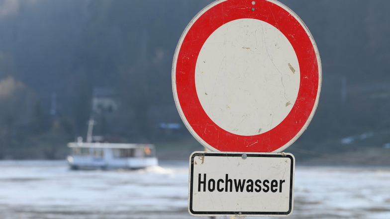 Ein Schild mit der Aufschrift "Hochwasser" steht am Ufer der Elbe in Bad Schandau.