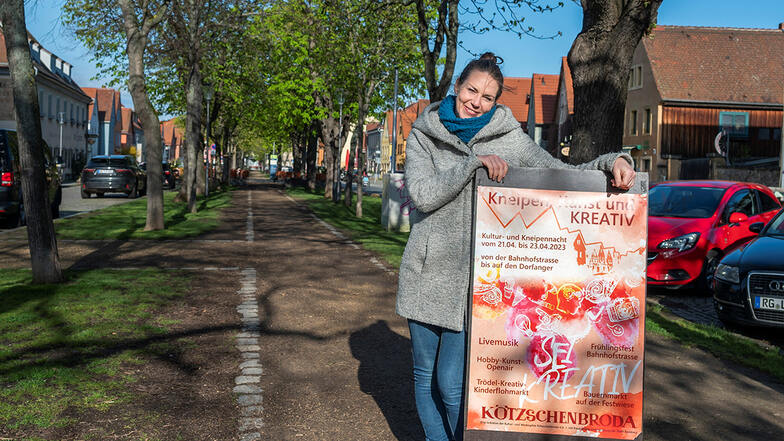 Mandy Hähnel von der Kultur- und Werbegilde steht mit einem Plakat auf dem Dorfanger Altkötzschenbroda. Sie hat das Frühlingsspektakel organisiert.