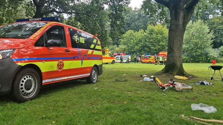 Einsatzfahrzeuge stehen nach einem Blitzeinschlag in einem Park in Delmenhorst. Mitglieder einer Familie, die sich unter einem Baum aufgehalten hatten, wurden verletzt. Eine Jugendliche ist nun an den Folgen gestorben.