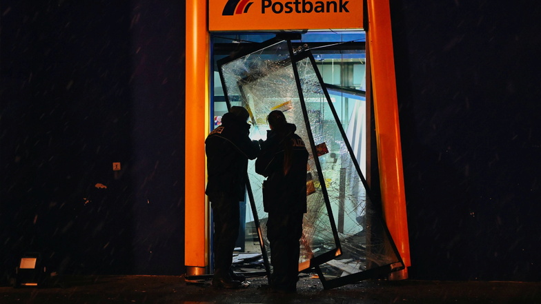 Polizisten stehen im zerstörten Eingangsbereich einer Bank. Dort haben Unbekannte einen Geldautomaten zerstört.