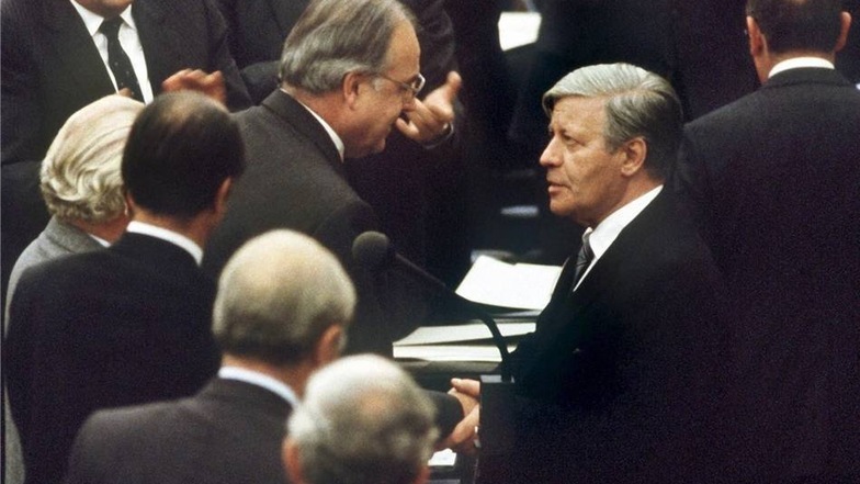 Das Archivbild vom 01.10.1982 zeigt den gestürzten Bundeskanzler Helmut Schmidt [r, SPD], der seinem Nachfolger Helmut Kohl [M,CDU] zu dessen Wahl gratuliert.