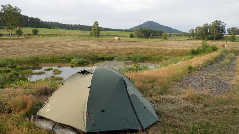 Zelten mit Teich und Ruzovy vrch (Rosenberg) auf einem privaten Grundstück in der Böhmischen Schweiz. 