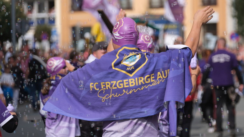 Sportler vom Verein Erzgebirge Aue schreiten beim Festumzug vom Tag der Sachsen durch das Stadtzentrum.