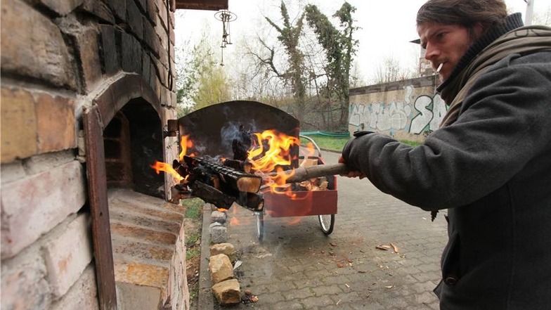 Philippe Ivoire füttert den Ofen mit brennenden Holzscheiten.