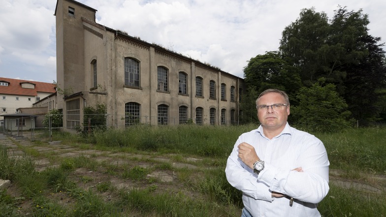 Die Tage der alten Fabrik, vor der Neukirchs Bürgermeister Jens Zeiler steht, sind gezählt. Die Gemeinde will die ehemalige Weberei abreißen lassen, um neue Gewerbeflächen zu erschließen. Das sorgt für Kritik.