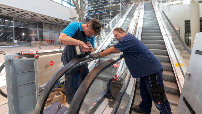 Mirko Rausch und Markus Schönenborn montieren den Handlauf der neuen Rolltreppe im zweiten Bauabschnitt des Kaufparkes.