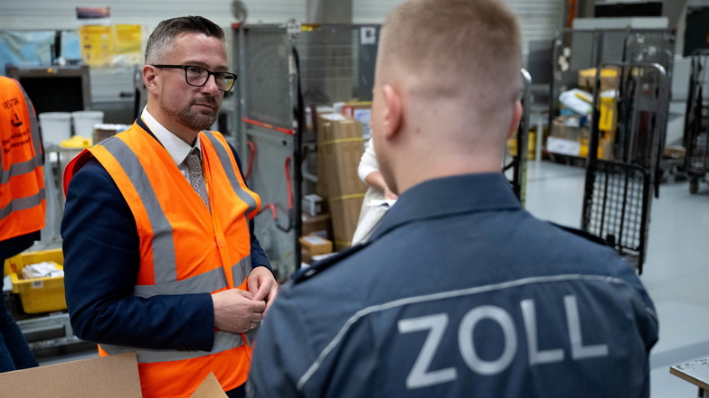 Martin Dulig (SPD, l), Wirtschaftsminister in Sachsen, unterhält sich im DHL-Hub am Flughafen Leipzig mit einem Zollmitarbeiter.