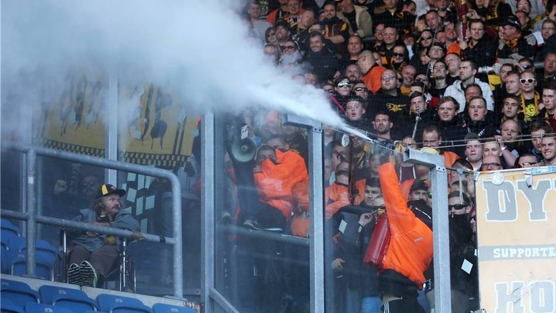 Ein Dynamo-Anhänger entleert einen Feuerlöscher - Polizei, Ordner und Hansa-Fans stehen daraufhin im Nebel.