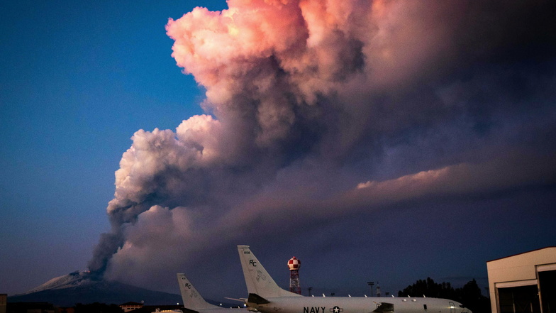 Flugzeuge stehen auf der US-Naval-Basis Sigonella, während im Hintergrund Rauschschwaden aus dem Vulkan Ätna aufsteigen.