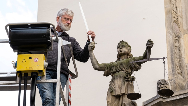 Hans Herbig, Inhaber der Firma Herbig Denkmalpflege aus Ostritz, fixiert das neue Schwert der Justitia an der Rathaustreppe am Görlitzer Untermarkt.