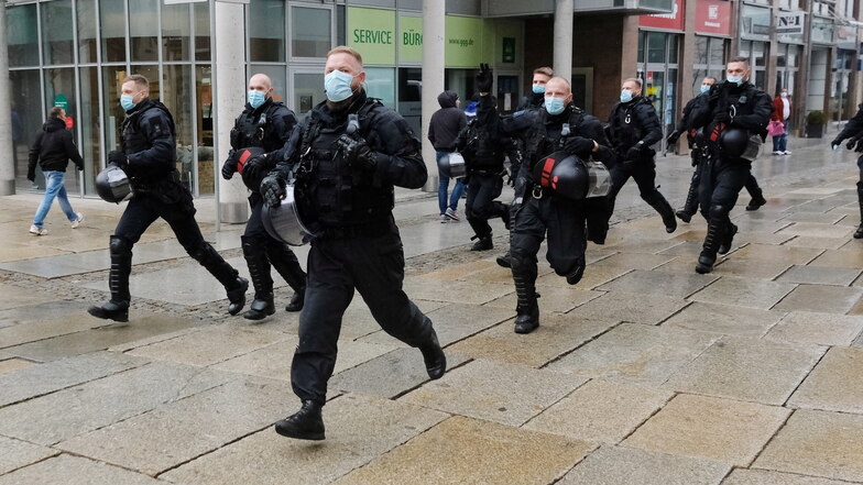 Polizisten laufen durch die Chemnitzer Innenstadt. Am Rande einer Kundgebung von Kritikern der Corona-Politik kam es zu Rangeleien mit der Polizei.