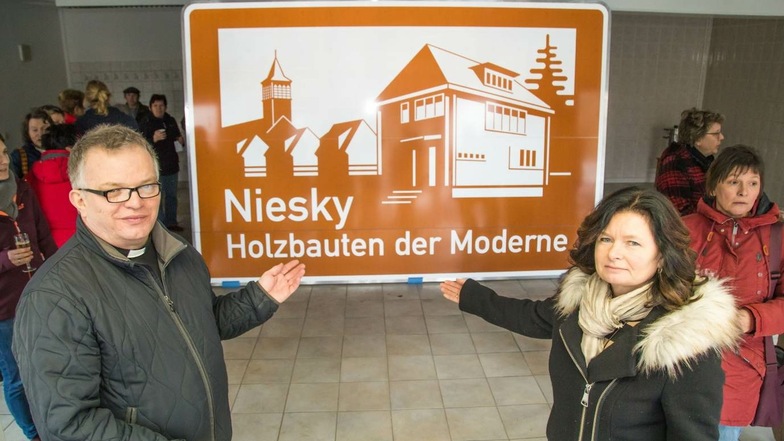 Die Nieskyer Oberbürgermeisterin Beate Hoffmann (rechts) und Pfarrer Krystian Burczek zeigen das Autobahnschild für Niesky – um das engagiert gekämpft wurde.