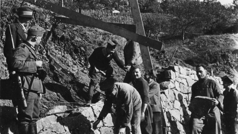 Französische Zwangsarbeiter werden von deutschen Wehrmachtssoldaten beim Terrassenbau in den Weinbergen bewacht.