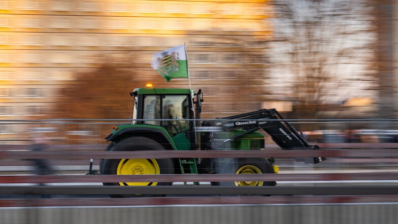 Ein Traktor fährt über die Carolabrücke und hat dabei eine Fahne des einstigen Königreiches Sachsen, Erkennungszeichen der rechtsextremen Kleinstpartei "Freie Sachsen", am Fahrerhaus montiert. Die Rechtsextremen versuchten die Bauernproteste zu kapern.