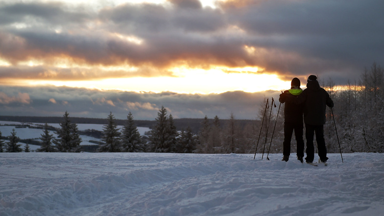 Was für ein Blick: Zwei Skifahrer beobachten den Sonnenuntergang in Schellerhau.