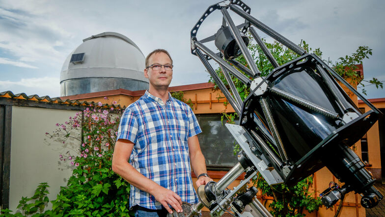 Torsten Müller zeigt sein großes Spiegelteleskop. Im Hintergrund ist die Kuppel seiner kleinen Sternwarte zu sehen, die er im Garten in Goldbach gebaut hat.
