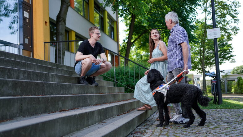 Andreas Schneider (62) geht mit seinem Blindenhund Morricone in ein Gebäude der Uniklinik. An den Treppen erklärt er Nele Mickel und Emanuel Lippmann, wie man Sehbehinderten hilft.