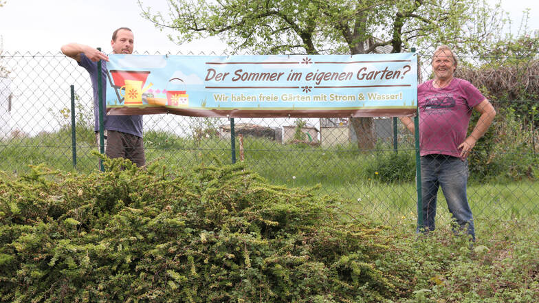 Heiko Thierbach (links) und Günter Glodek zeigen ein Werbebanner, mit dem die Gartenanlage „Am Wiesengrund“ in Döbeln Interessenten anlocken will.