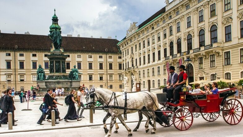 Ein Fiaker fährt Touristen während einer Stadtrundfahrt in einer Pferdedroschke durch Wien.