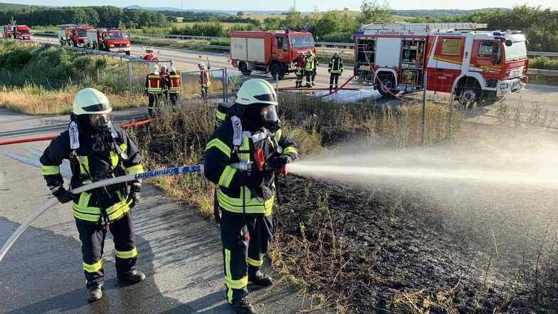 Mehrere Feuerwehrleute waren am Dienstag neben der A9 bei Leipzig im Einsatz, um eine brennende Böschung zu löschen.. Zwei Lkw-Insassen hatten zuvor brennendes Material neben die Autobahn geschmissen.
