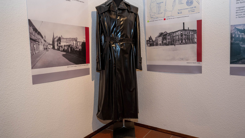Ein schwarzer Mantel aus Igelit. Dieser ist sehr oft getragen worden, da im inneren deutliche Spuren sichtbar sind.