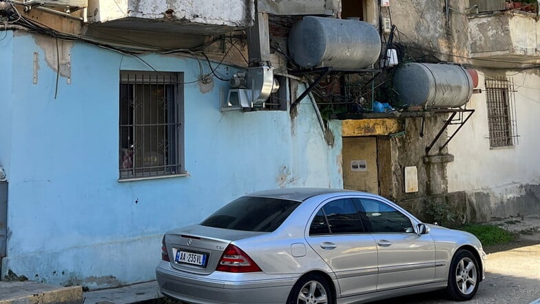 Albanische Kontraste: Wohlstandssymbol vor einem heruntergekommenen Wohngebäude.