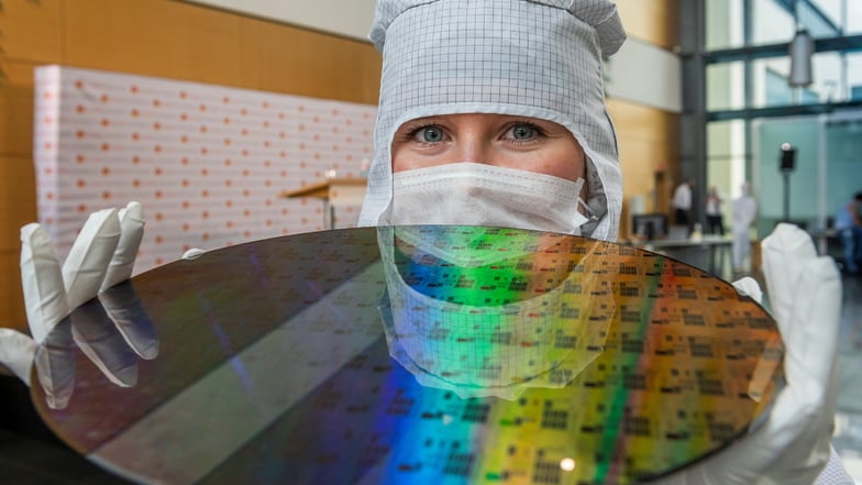 Eine Auszubildende präsentiert einen 300-Millimeter-Wafer in der Chipfabrik von Globalfoundries.  Der US-Chiphersteller wie auch die anderen Produzenten werden ihre Azubis künftig im SAM ausbilden.