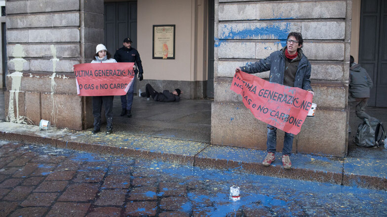 Klima-Demonstranten von "Letzte Generation" halten Plakate mit der Aufschrift "Kein Gas und keine Kohle" vor dem mit Farbe beschmierten Opernhaus Scala hoch.