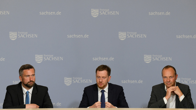 Michael Kretschmer (CDU, mitte), Ministerpräsident von Sachsen, Martin Dulig (SPD, links), Wirtschaftsminister von Sachsen, und Wolfram Günther (Bündnis90/Die Grünen) sitzen an einem Tisch.