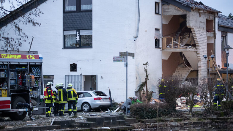 Feuerwehrleute stehen vor dem von einer Gasexplosion stark beschädigten Haus. Ein Feuerwehrmann kam ums leben und drei weitere wurden verletzt,