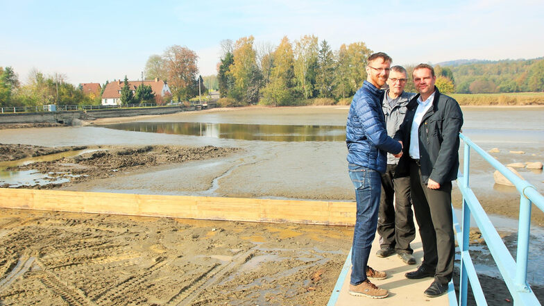 Vereinschef Sven Heinrich, Gerald Meyer und Bürgermeister Stefan Schneider sind mit der Entwicklung im Naturbad Buschmühle sehr zufrieden. Hinter ihnen ist die neue Schlammsperre zu sehen.